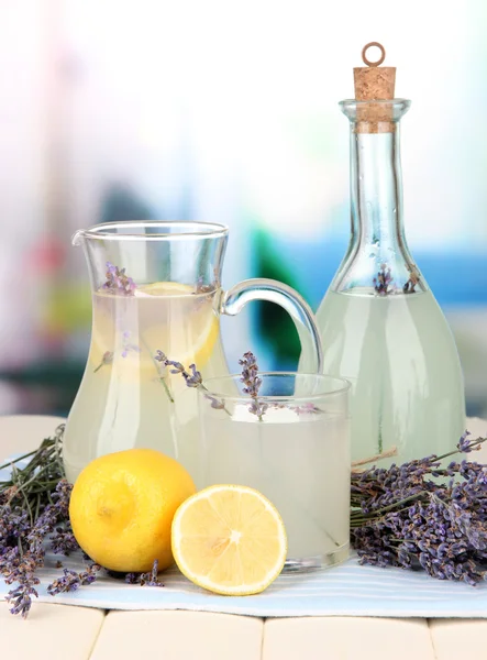 Limonata di lavanda in bottiglia di vetro e brocca, su tovagliolo, su sfondo brillante — Foto Stock