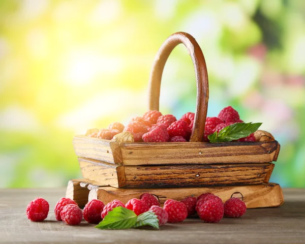 Zralé sladké maliny v koši na dřevěný stůl, na zeleném pozadí — Stock fotografie