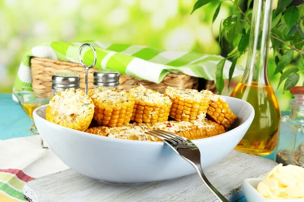 Aromatisierter gekochter Mais auf Teller auf Holztisch vor natürlichem Hintergrund — Stockfoto