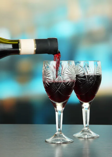 Rött vin som hälls i glas vin, på ljus bakgrund — Stockfoto