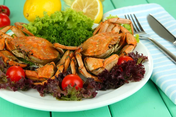 Crabes bouillis sur assiette blanche avec feuilles de salade et tomates, sur fond de table en bois — Photo