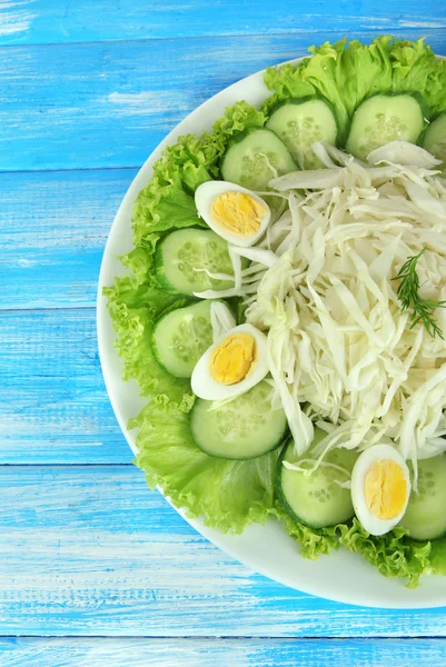 Delicious salad with eggs, cabbage and cucumbers on blue table — Stock Photo, Image