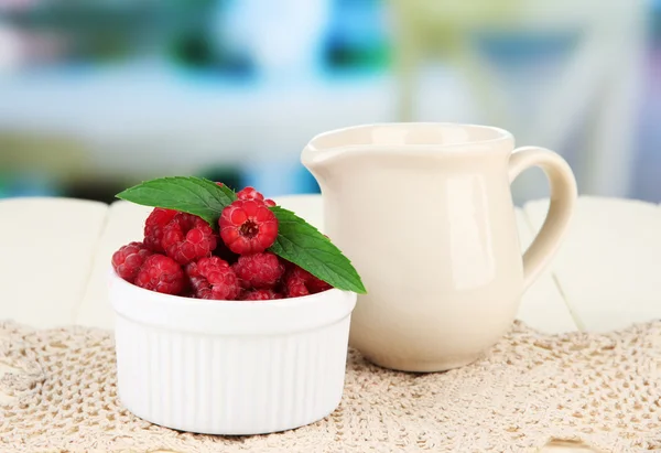 Frische Himbeere und Sahne im Krug auf Holztisch, auf hellem Hintergrund — Stockfoto