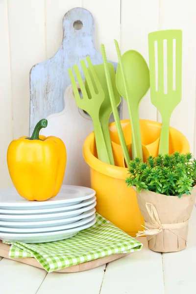 Plastic kitchen utensils in cup on wooden table — Stock Photo, Image