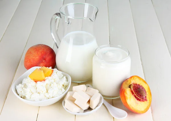 Frische Milchprodukte mit Pfirsichen auf Holztisch in Großaufnahme — Stockfoto