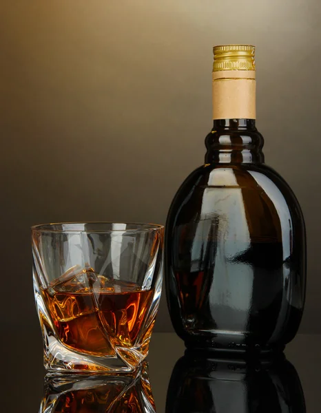 Glass of liquor with bottle, on dark background — Stock Photo, Image