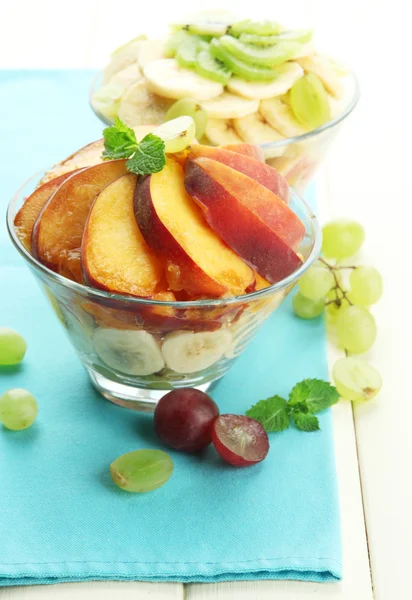 Ensalada de frutas sabrosas en cuencos de vidrio, sobre mesa de madera blanca — Foto de Stock