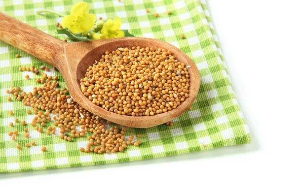 Mustard seeds in wooden spoon with mustard flower isolated on white — Stock Photo, Image