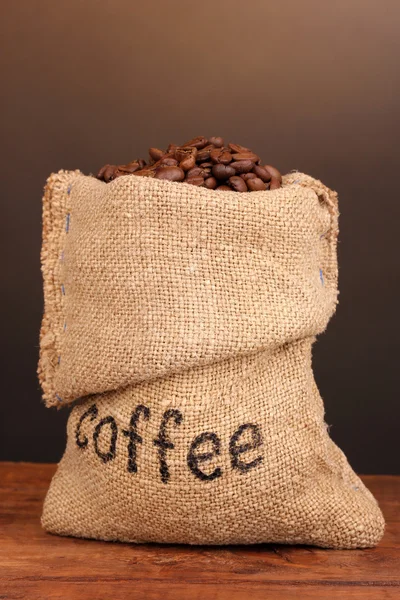 Coffee beans in bag on table on dark background — Stock Photo, Image