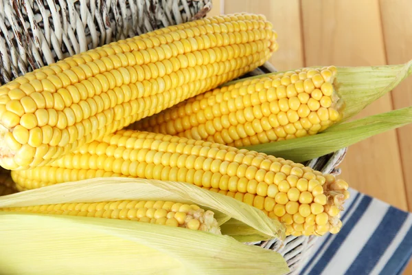 Crude corns in basket on napkin on wooden table — Stock Photo, Image