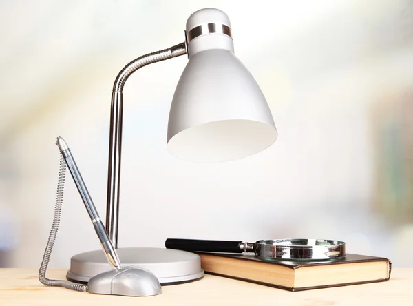 Table lamp and book on desk in room — Stock Photo, Image