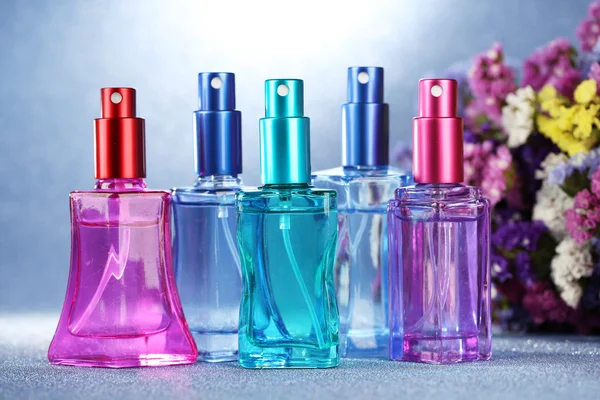 Γυναικών άρωμα στο όμορφο μπουκάλια και λουλούδια σε μπλε φόντο — Φωτογραφία Αρχείου