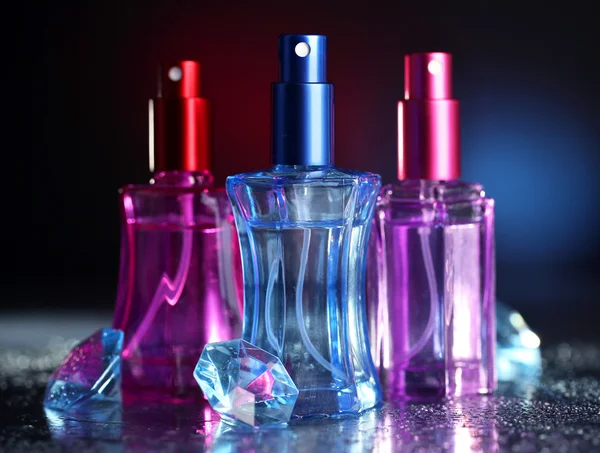 Femmes parfum dans de belles bouteilles sur fond sombre avec de la lumière de couleur — Photo