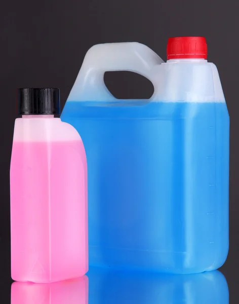 Синие и розовые жидкости для автомобиля в канистрах на черном фоне — стоковое фото