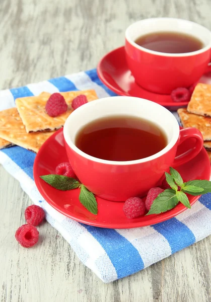 Cups of tea with cookies and raspberries on table close-up — Stock Photo, Image