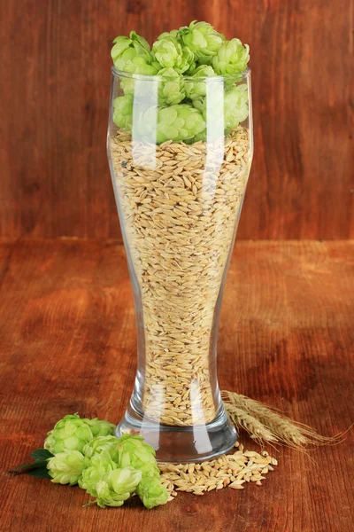 Glass of fresh green hops and barley, on wooden background — Stock Photo, Image