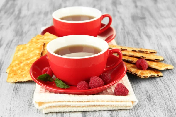 Tazas de té con galletas y frambuesas en primer plano de la mesa — Foto de Stock