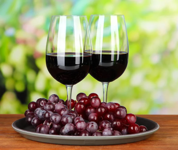 Ripe grapes and glasses of wine, on bright background — Stock Photo, Image