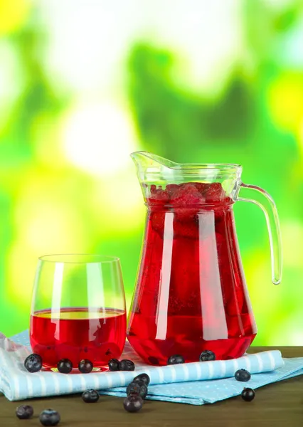 Pitcher et verre de compote sur serviette sur table en bois sur fond nature — Photo