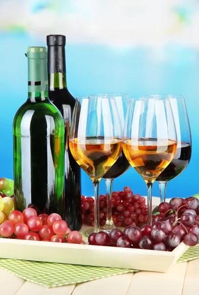 Wijn flessen en glazen wijn op het dienblad, op lichte achtergrond — Stockfoto