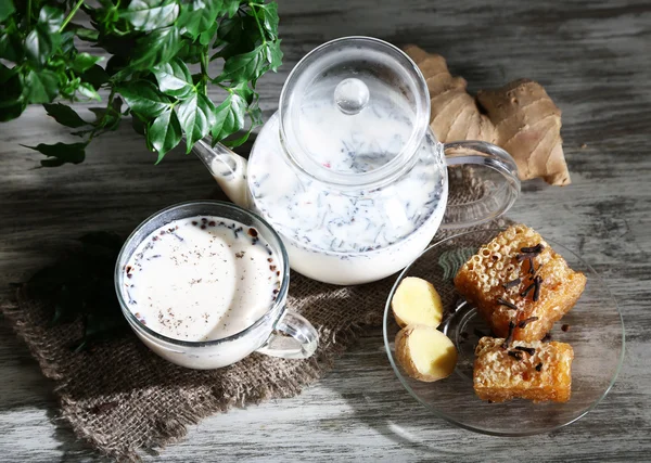 चाय का कप और चाय के साथ दूध और मसाले लकड़ी की मेज के थैला पर — स्टॉक फ़ोटो, इमेज