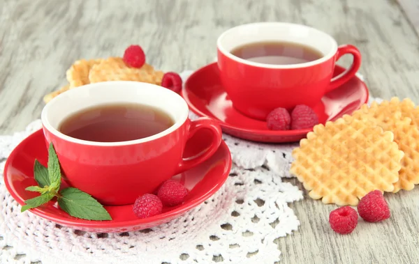 Kopjes thee met koekjes en frambozen op tabel close-up — Stockfoto