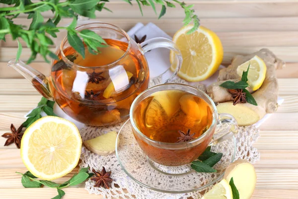 Wasserkocher und Tasse Tee mit Ingwer auf Serviette auf Holztisch — Stockfoto