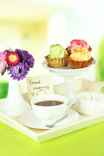 Xícara de chá com bolos na bandeja de madeira na mesa no quarto — Fotografia de Stock