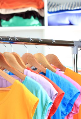 çeşitli ahşap askı raf arka plan üzerinde rahat t-shirt