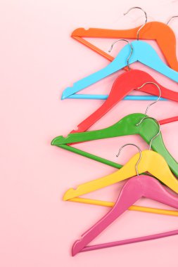pembe bir arka plan üzerinde renkli elbise askıları