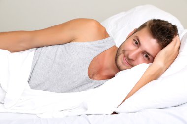 Yakışıklı genç adam yatakta.