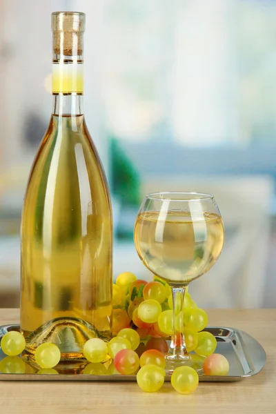 Белое вино в стакане с бутылкой на спинке на заднем плане — стоковое фото