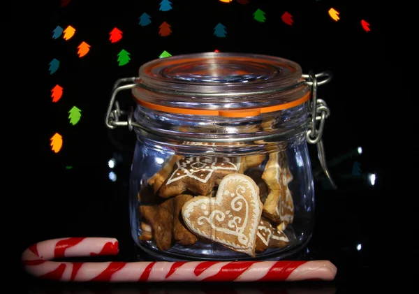 Tasty cookies in glass bottle on blur lights background — Stock Photo, Image