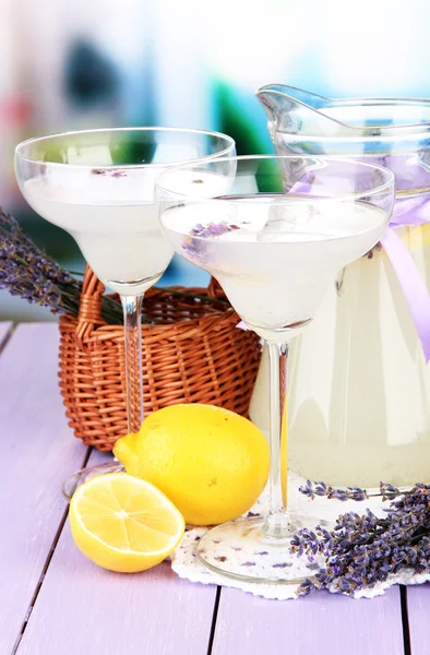 Limonada de lavanda em jarro de vidro e copos de coquetel, em fundo brilhante — Fotografia de Stock