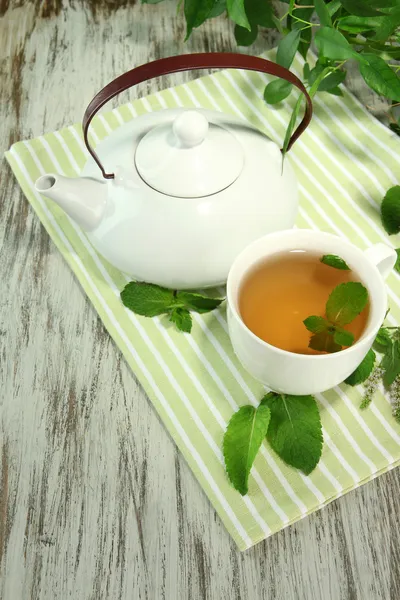 Teapot and cup of herbal tea with fresh mint flowers on wooden table — Stock Photo, Image