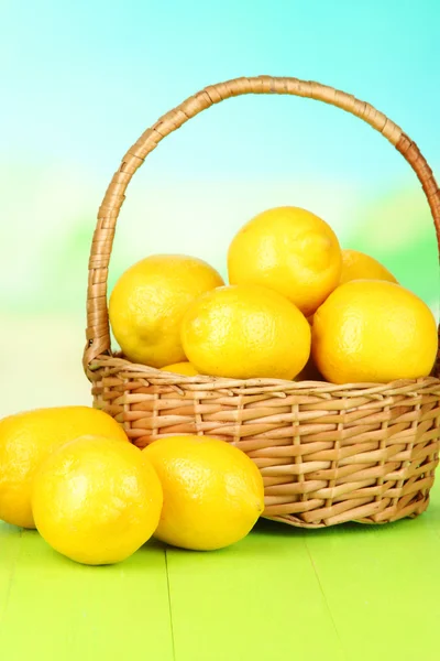 Limones maduros en canasta de mimbre sobre mesa sobre fondo brillante —  Fotos de Stock