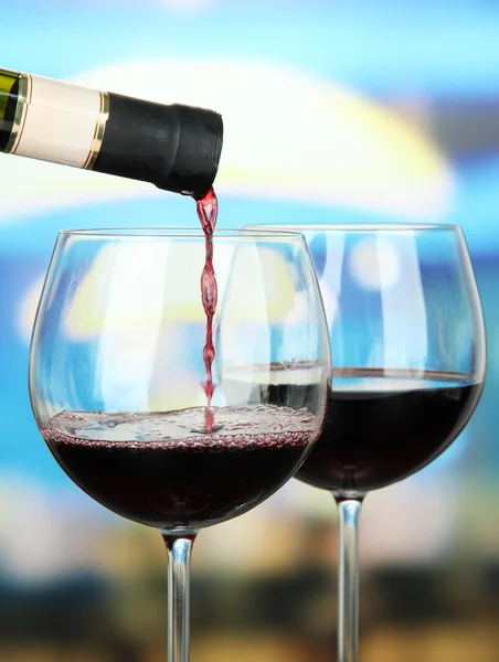 Червоне вино вливають у келих для вина, на яскравому фоні — стокове фото