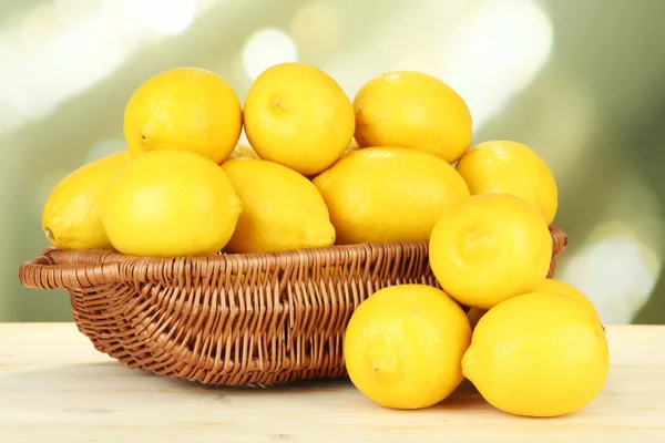 Dojrzałe cytryny w wiklinowym koszu na stole na jasnym tle — Zdjęcie stockowe