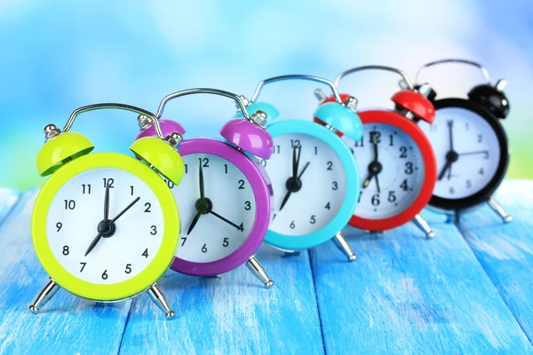 Colorful alarm clocks on table on blue background — Stock Photo, Image