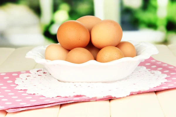 Eggs in plate on wooden table on window background — Stock Photo, Image