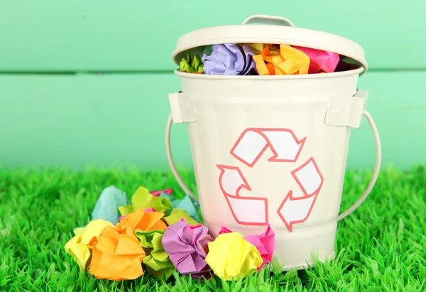 Reciclagem bin na grama verde na cor de fundo de madeira — Fotografia de Stock