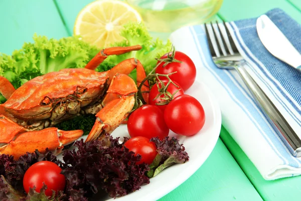 Варёный краб на белой тарелке с листьями салата и помидорами, на деревянном фоне стола — стоковое фото