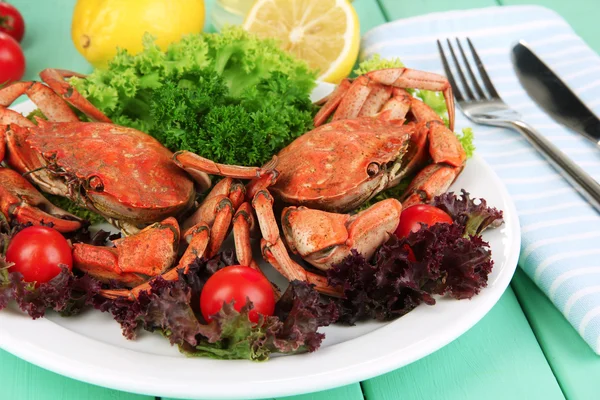 Crabes bouillis sur assiette blanche avec feuilles de salade et tomates, sur fond de table en bois — Photo