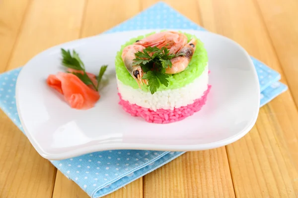 Colored rice on plate on napkin on wooden table — Stock Photo, Image
