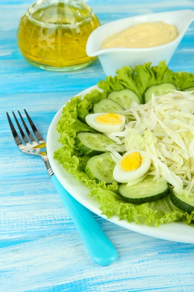 Вкусный салат с яйцами, капустой и огурцами на синем столе — стоковое фото