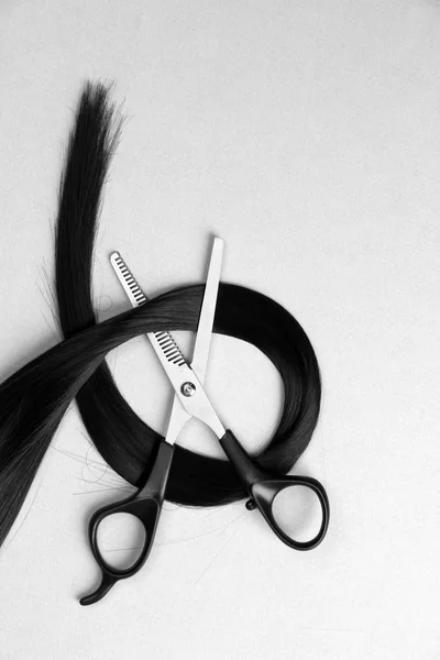 Tesoura e cabelo no fundo cinza — Fotografia de Stock