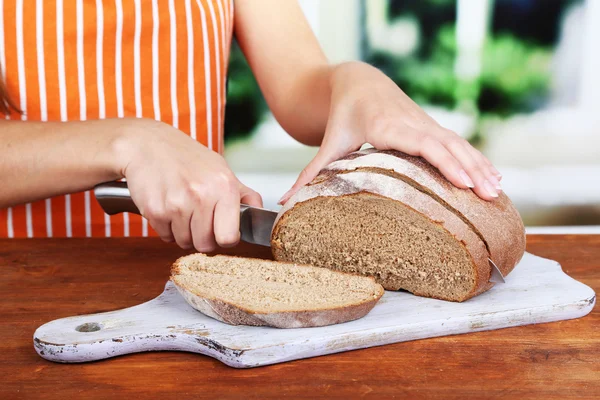 Taglio del pane su tavola di legno su tavola di legno su fondo finestra — Foto Stock