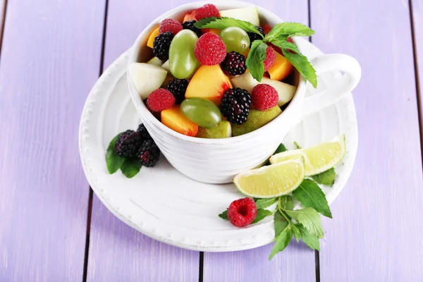 Fruit salad in cup on wooden table — Stock Photo, Image