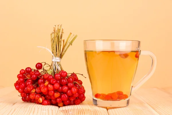 Tè con viburno rosso sul tavolo su sfondo beige — Foto Stock