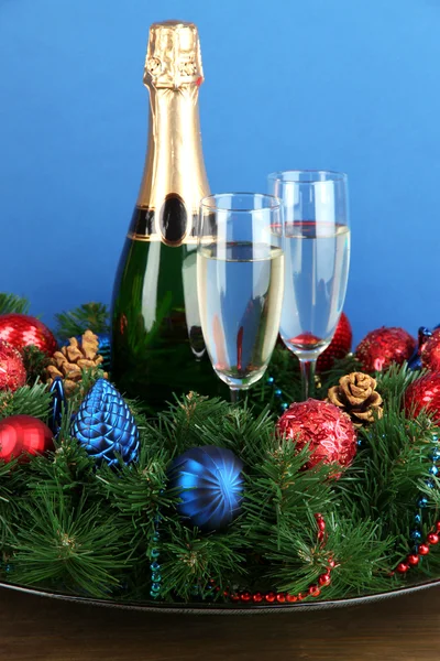 Schöner Weihnachtskranz in Komposition mit Champagner auf blauem Hintergrund — Stockfoto